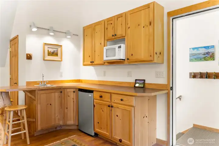Guest house kitchen featuring warm wood cabinetry, efficient layout, and ample storage—bright and functional space designed for comfortable, independent living