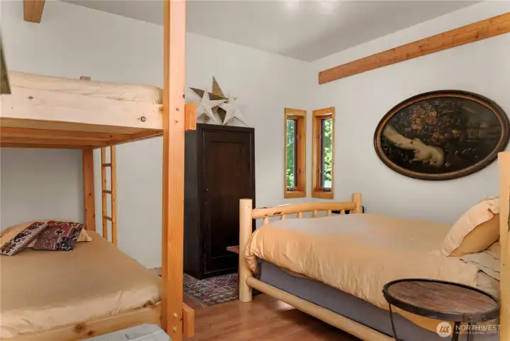Bunk room with warm wood accents and efficient layout, offering cozy, flexible sleeping space ideal for guests, kids, or overflow accommodations