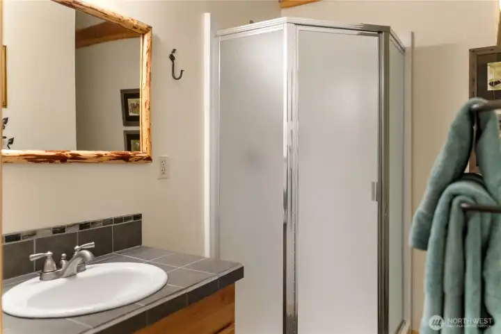 Bunk room ensuite bathroom featuring a walk-in shower, vanity with storage, and clean, functional finishes—convenient and comfortable for guests