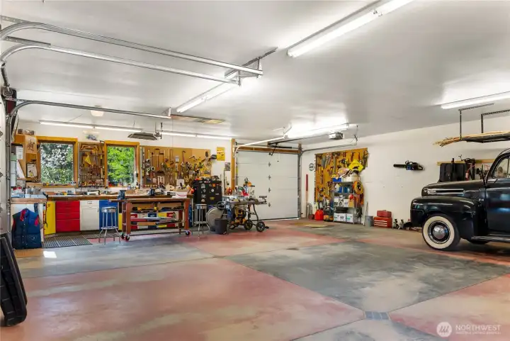 Expansive heated garage and workshop with high ceilings and ample room for vehicles, tools, and projects—plus extra covered storage out back, a dedicated wood shed, and additional attic storage for year-round functionality
