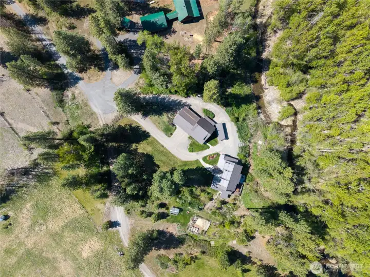 Overhead view showcasing the thoughtful layout, circular drive, and relationship between the home, outbuildings, and surrounding land