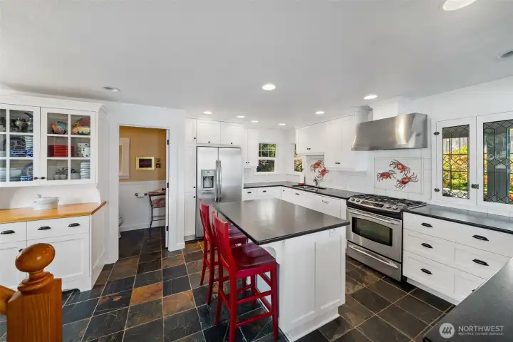 Tastefully remodeled kitchen with timeless choices. Handsome slate tile flooring, crisp, white cabinetry, stainless appliances and custom, full-height tile backsplash