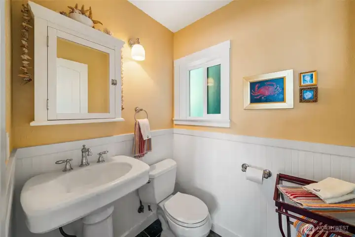 Convenient main floor powder room with charming, coastal wainscoting, pedestal sink