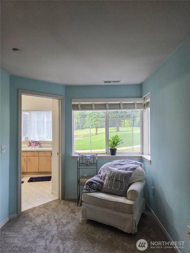 Peaceful reading corning in the primary ensuite with door leading to the 3/4 bathroom.  Notice the view of the golf course from these windows.