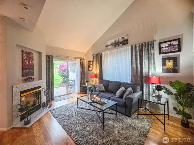 The living room is just steps away from the entry way and dining room.  Soaring ceilings, wood plank flooring,   two-way gas fireplace and slider to the back patio compliment this cozy and inviting room.