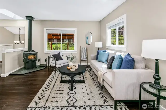 Open living space; great light- newer finishes, plus access to a covered deck. Notice the cozy wood stove / fireplace and A/C.
