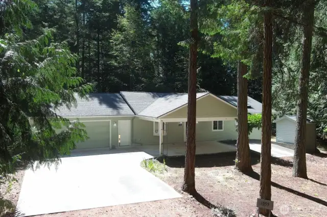 Front of house. One level living. Large parking pad goes to the oversized garage (26 feet w by 26 feet depth). The covered carport allows extra parking as well as a pass-through area for a circular driveway.