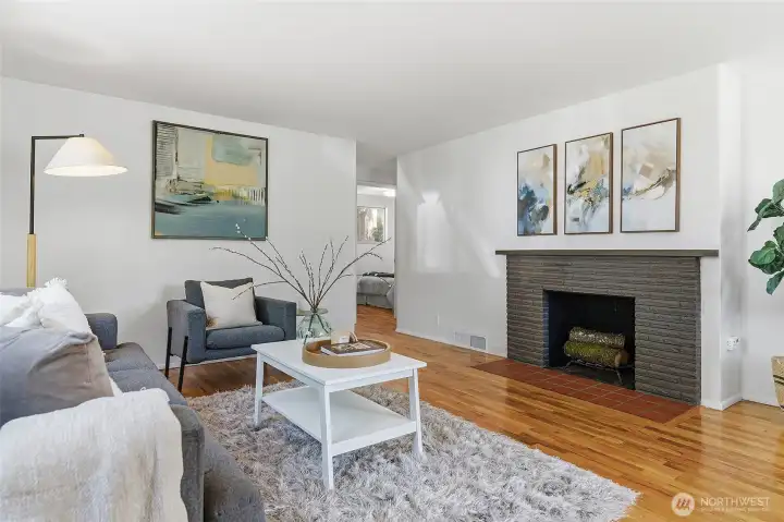 Formal living room with a wood burning fireplace, hardwood floors and opens to the dining area with views of Cromwell Park and light and bright western exposure