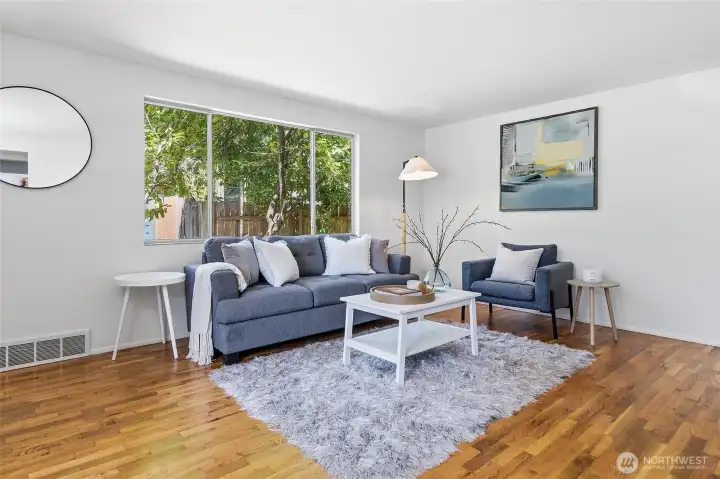 Formal living room with a wood burning fireplace, hardwood floors and opens to the dining area with views of Cromwell Park and light and bright western exposure