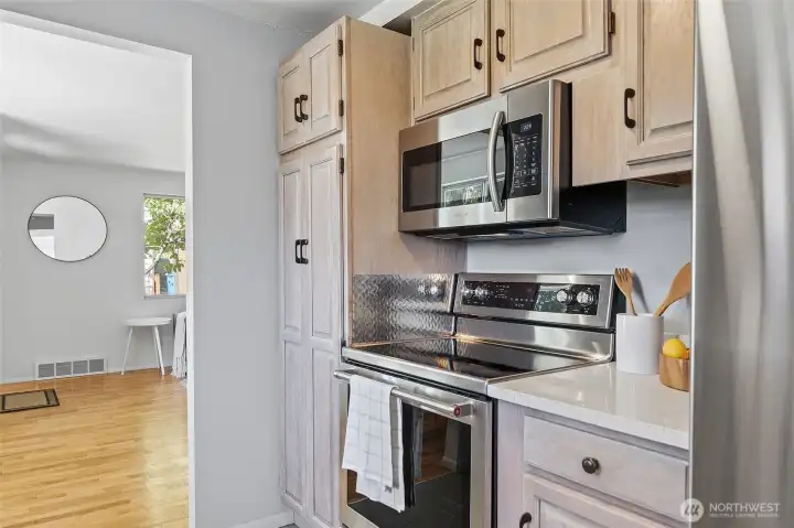 Updated galley style kitchen with quartz counters, refaced cabinets and stainless appliances opens to family room and to the dining area/living room.