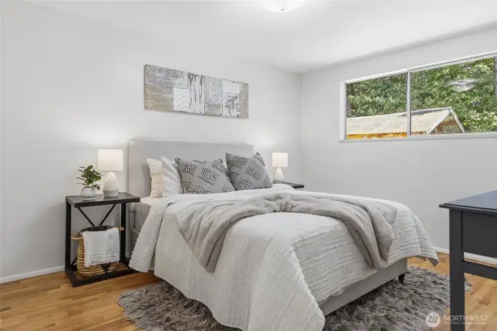 Main floor bedroom #1 with hardwood floors and views out to the backyard.
