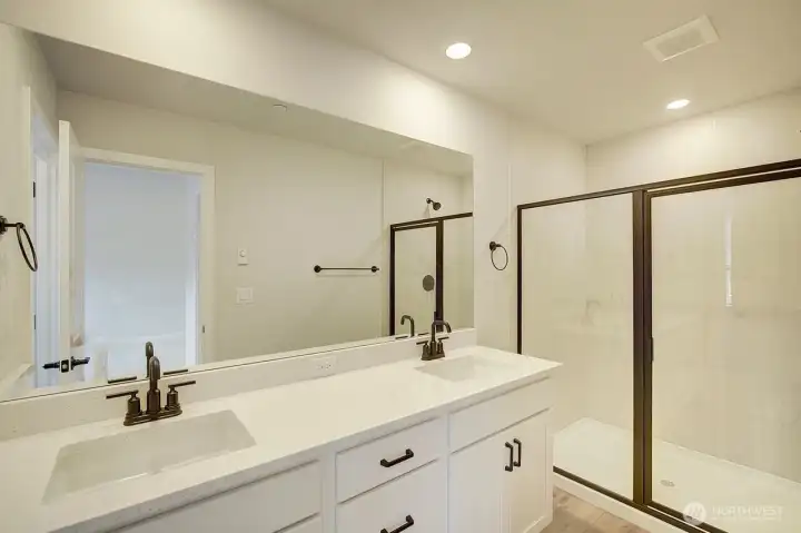 Primary suite bath with large walk in shower and double vanitiy.,