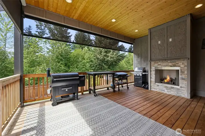 Enjoy outdoor living year round with remote powered floor to ceiling screens, gas fireplace, and warm wood decking.