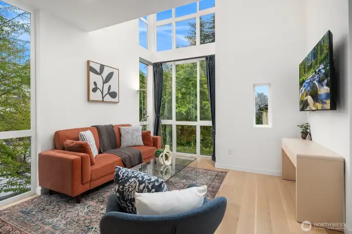 Light-filled living space with soaring floor-to-ceiling windows, vaulted ceilings, and engineered hardwood floors creating an airy, expansive feel in the heart of this modern urban home.