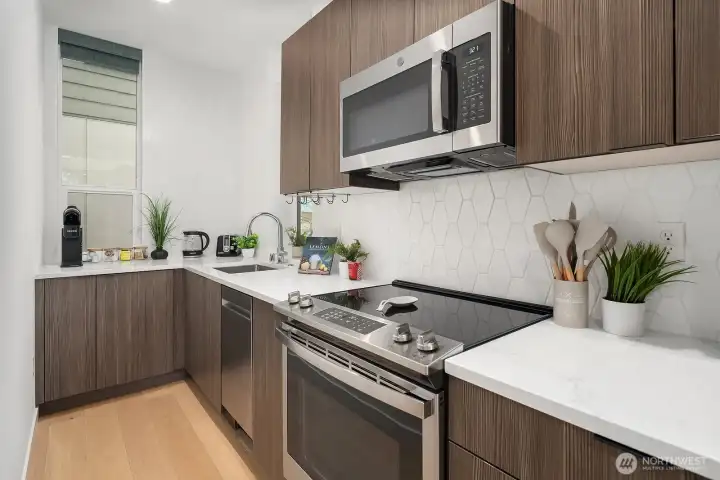 Efficiently designed kitchen with rich dark cabinetry, quartz countertops, stainless steel appliances, and a bright, clean aesthetic perfectly suited for urban living.