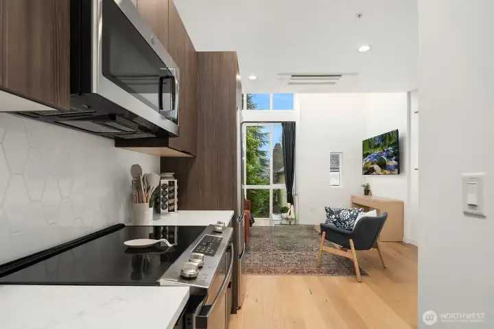 Stylish galley kitchen with dark cabinetry, stainless steel appliances, and a seamless open flow into the dining and living areas, maximizing both function and space in this modern urban home.