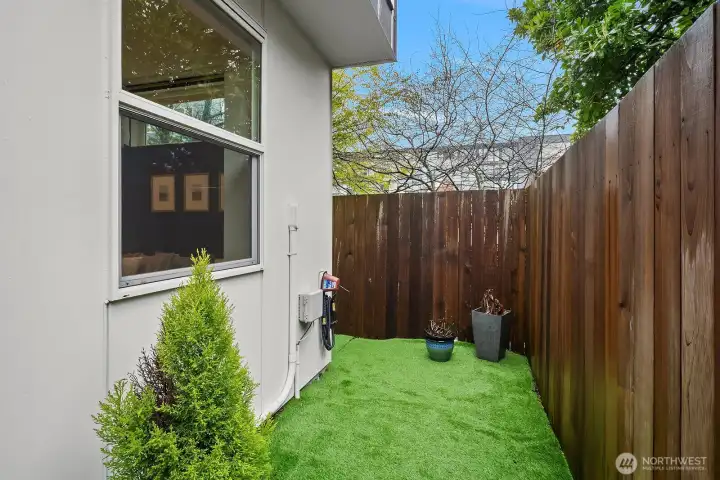 Charming private turf yard with lush greenery, a blooming tree, and a fully fenced setting offering a rare and tranquil outdoor escape in the heart of the city.