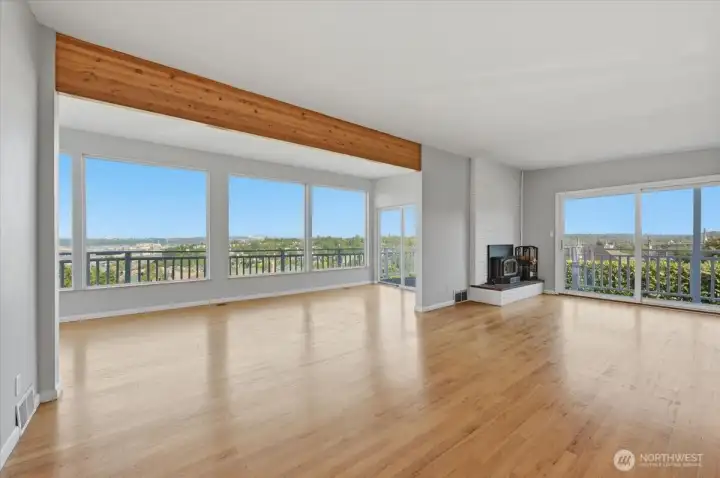 The living room showcases one of Seattle's most sought-after features, a stunning connection to the outdoors! Floor to ceiling windows and multiple sliding glass doors flood the expansive area with natural light while framing sweeping views.