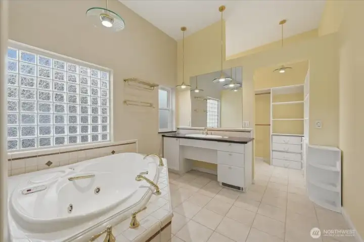 A luxurious primary bath features a delightful jet tub, exquisite lighting and walk-in closet.