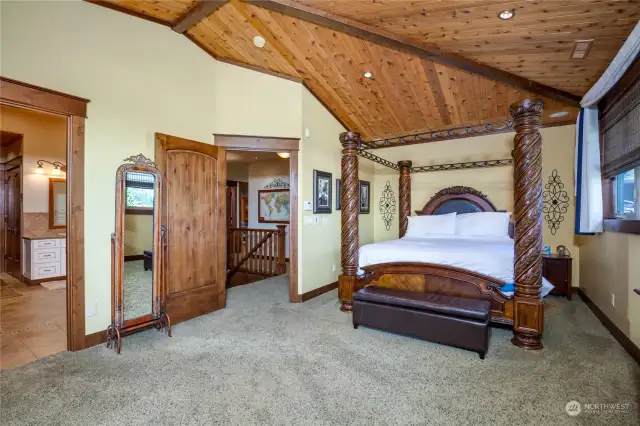 The primary bedroom features a vaulted and segmented ceiling, with wood soffits and warm carpeting.  There is recessed can lighting and Sonos In Room Audio sound