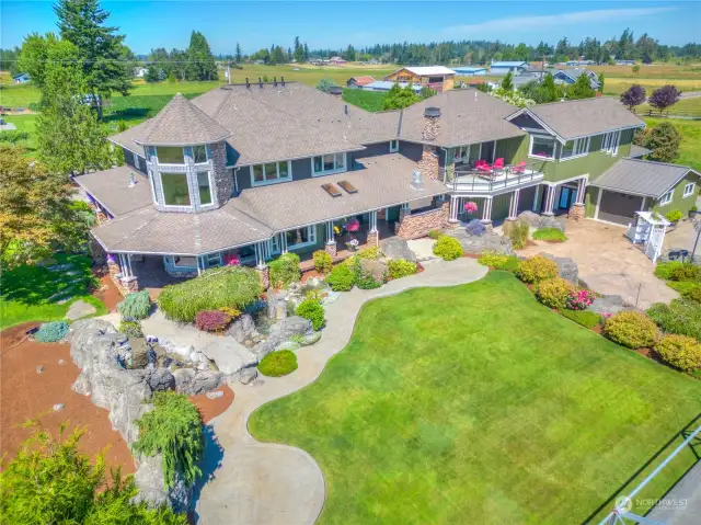 An exterior view of the property featuring the rear areas of the residence, with extensive stamped concrete walks, professional landscaping and a water feature