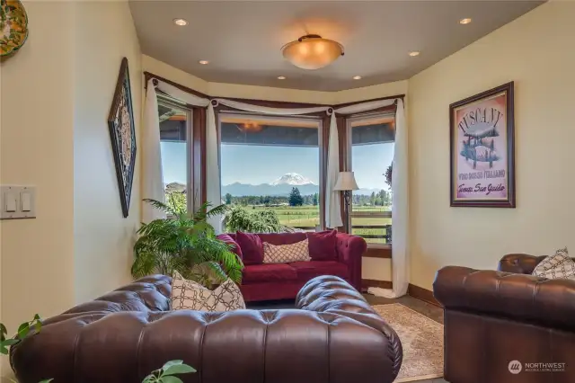 A sitting room with bay windows and a superb mountain view; notice the central light fixture surrounded by recessed can lighting