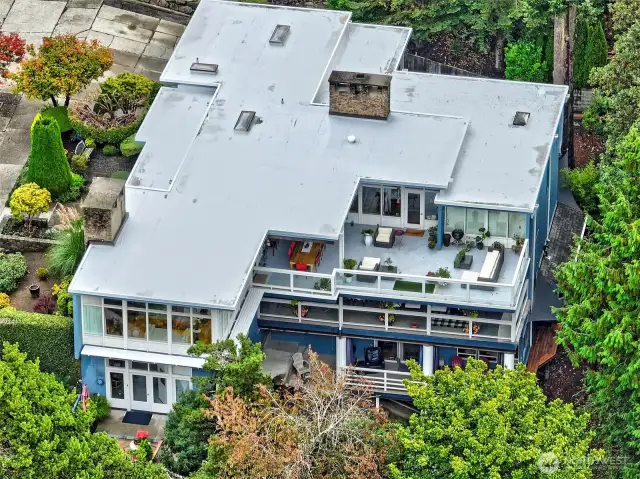 A rare aerial reveals the full volume of this four-level residence—nearly 7,700 square feet across five bedrooms, four baths, multiple gathering rooms, offices, and bonus spaces. Three outdoor decks crown the structure, including an oversized rooftop terrace. The roof itself was recently replaced, underscoring the home’s blend of enduring design and thoughtful stewardship. A true legacy property, designed for flexibility, creativity, and multi-generational living.