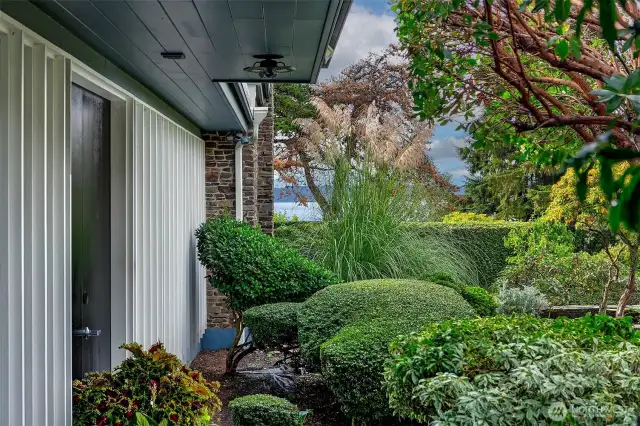 Sculpted evergreens, vintage screen block, and finely detailed eaves define the eastern garden entry—an interplay of architecture and horticulture that nods to Japanese influences and mid-century restraint. Every approach to 4221 W Armour is intentional, layered, and quietly cinematic.