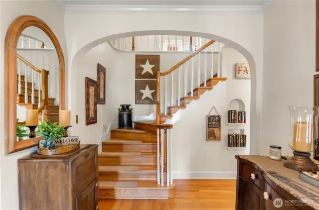 Welcoming entry with hardwood floors, curved staircase, and arched detailing—an elegant first impression that sets the tone for this timeless home.