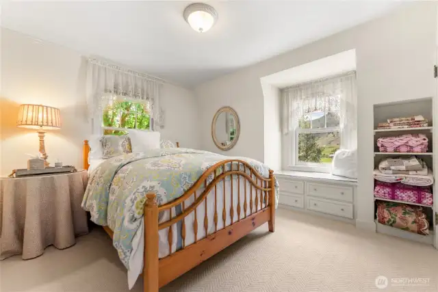 Upstairs guest room; peaceful and light-filled, this guest room offers a cozy retreat with vintage shelving and pastoral vistas of the rolling hills and river beyond.