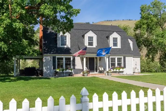 Classic 1930s farmhouse with fresh exterior paint, charming dormers, and a brand-new roof—timeless style and modern care in a serene, tree-lined setting.