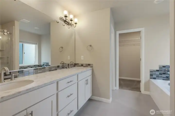 Nice size primary bathrrom w/quartz counter, dual sinks, soaker tub & tile floor.  Walk in closet straight ahead