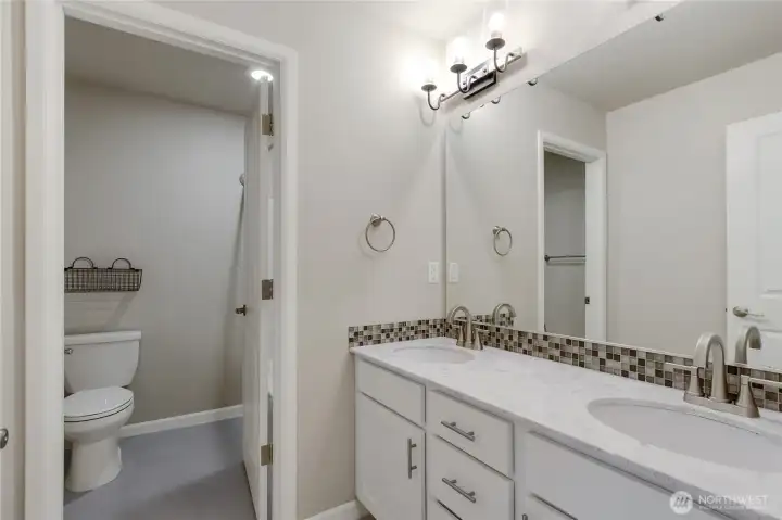 Upstairs bathroom has dual sinks, quartz counters, tile floors and separate shower, tub and toilet area