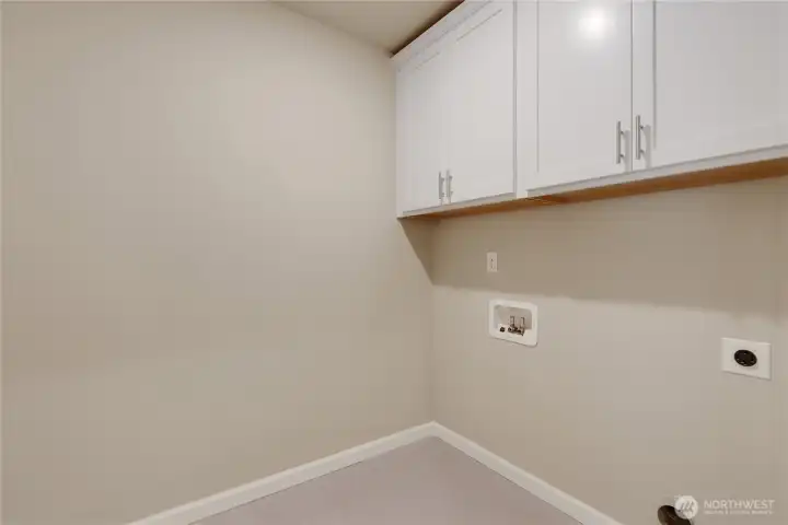 Upstairs laundry room with tile floors and storage