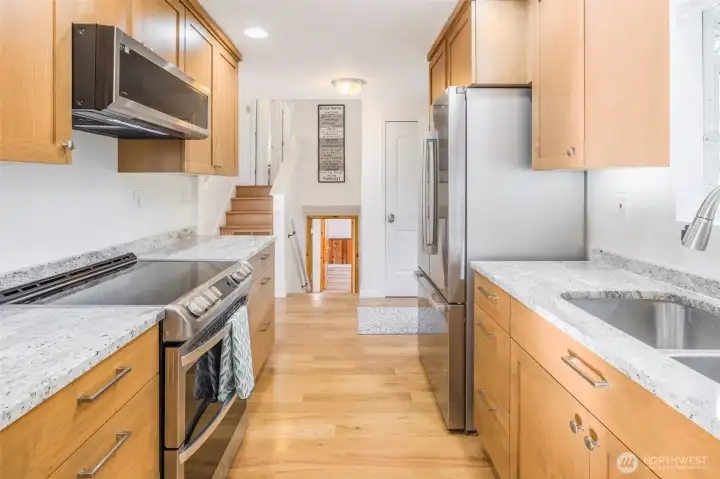 Looking through the kitchen toward the stairs going up to 3 bedrooms and full bath and down to Family room