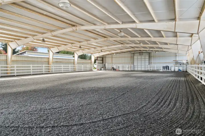 80 x 150 clear span steel construction, it offers sand and ground rubber footing for optimal traction and comfort. Entrance doors at both ends provide easy access, while vapor lighting ensures excellent visibility. The arena is equipped with a sprinkler system to minimize dust, and the interior walls are finished with vinyl fencing, enhancing both safety and aesthetics.