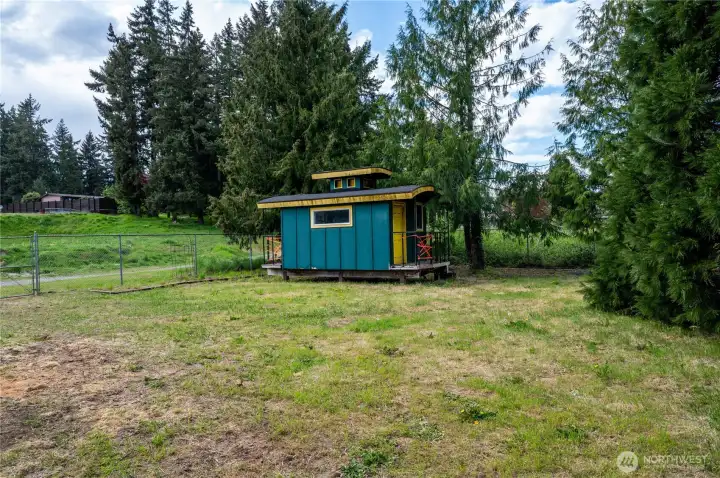 North side. The outbuilding was custom built to look like a caboose, which stays with the property.  WARNING, DO NOT STEP ON DECK AS IT'S NOT SAFE. Please do not remove the red tape.