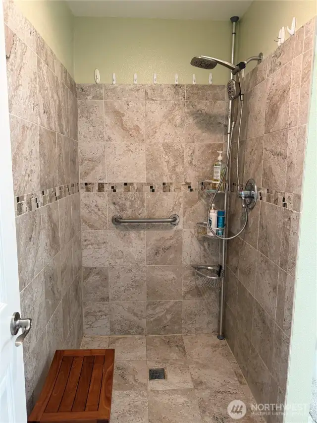 Large walk-in shower with beautiful decorative tile. Multi-head shower.