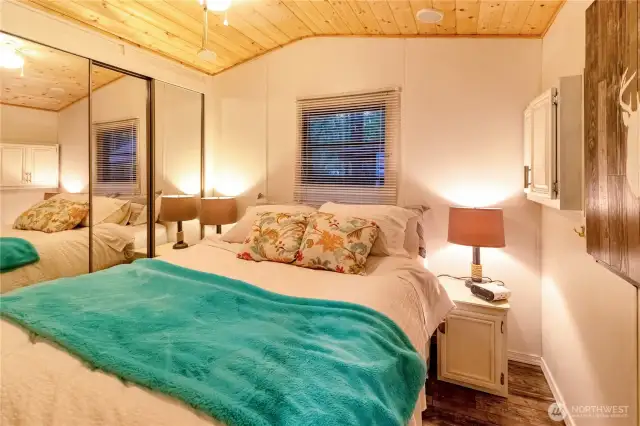 Primary bedroom with mirrored closet doors and vaulted ceilings