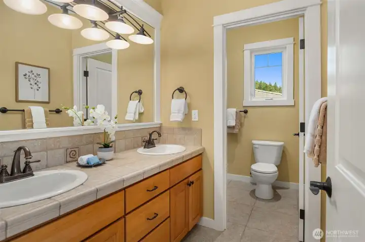 Well-appointed with dual vanities and a separate water closet, the upstairs hall bath is thoughtfully designed to comfortably serve the secondary bedrooms. Well-appointed with dual vanities and a separate water closet, the upstairs hall bath is thoughtfully designed to comfortably serve the secondary bedrooms.
