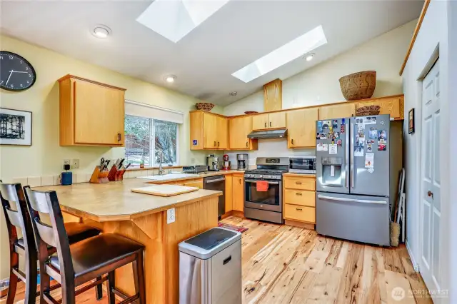 Stainless steel appliances and plenty of cabinet storage. More skylights and a pantry on the right.