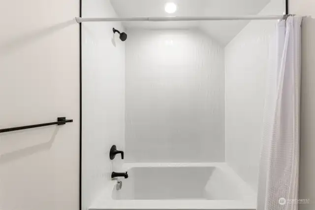 Unwind in this minimalist bath. Fresh white tiles and matte black fixtures create a modern, spa-like feel.