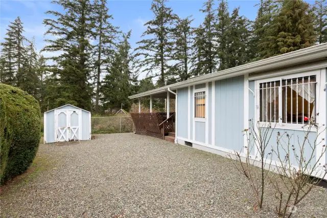 Toward the back of your side yard is a storage outbuilding (not to be confused with the spacious shop/storage room at the back of the carport!) At the rear of the home, you see the spacious deck.