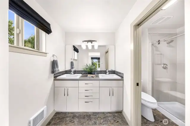 Double vanity, tiled spacious shower with glass door.