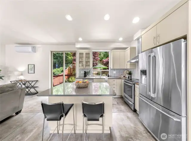 Beautiful kitchen with an island, quartz countertops, stainless steel appliances, gorgeous backsplash.