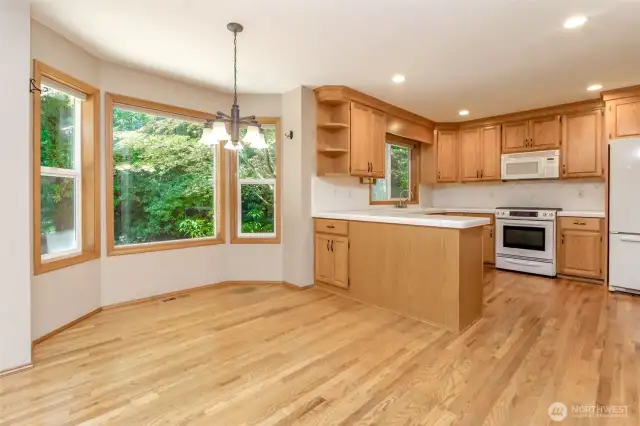Wonderful kitchen with hardwood floors and cabinets, tile countertops and recessed lighting. Informal dining area in the foreground...