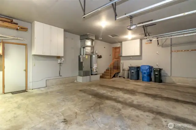 Garage with storage cabinets, gas furnace, new gas water heater and door to the backyard walkway.