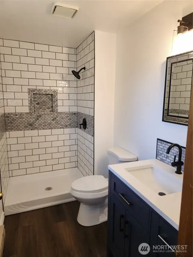 Renovated ensuite bath with tiled shower and functional vanity. Open up vanity under sink and notice the pullout which has phone charging units and storage for items.