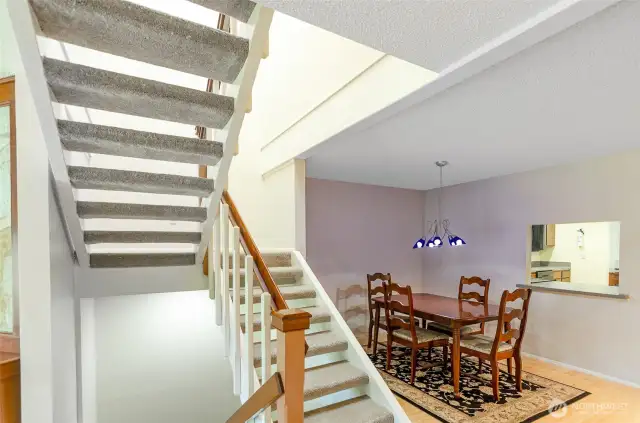Open staircase lead to upper and lower living spaces.  Dining room has window access to kitchen.