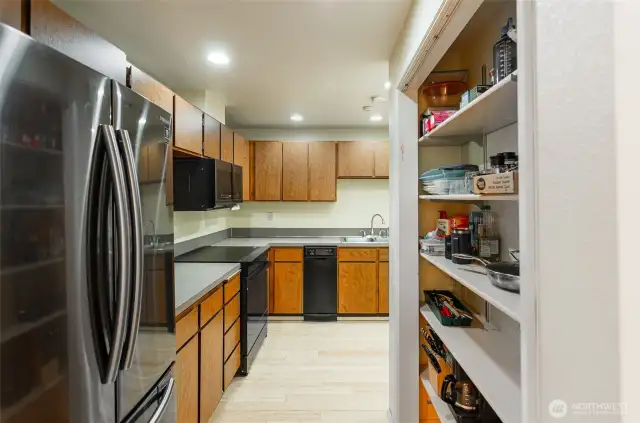 Entry to the kitchen from the hallway.  Notice the bamboo flooring and modern new refrigerator.  Open shelving for storage.